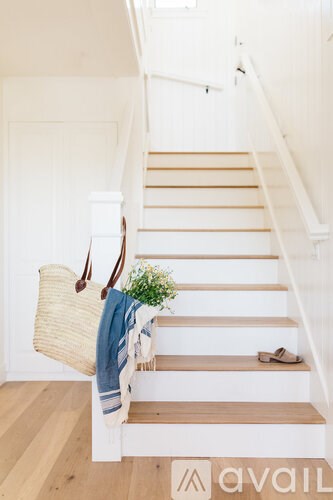 A staircase with a basket, a plant, and a towel hanging on the banister.