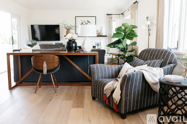 A living room with a black couch and a wooden desk.