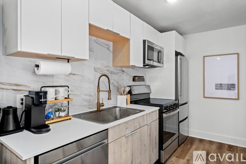 A kitchen with white cabinets and a marble backsplash.
