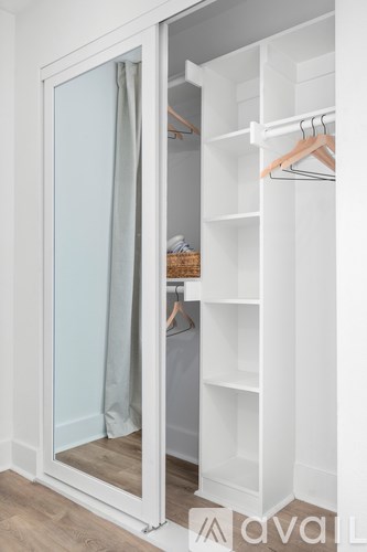 A white closet with a mirror and shelves.
