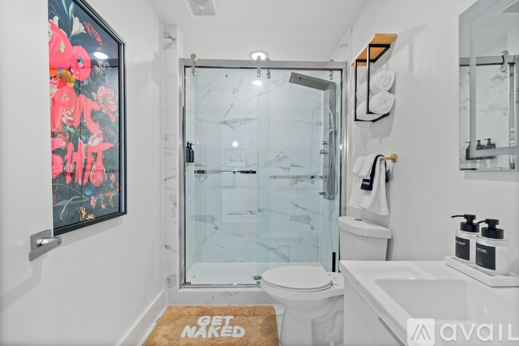 A bathroom with a toilet, sink, and a glass shower door.