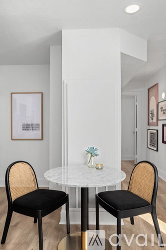 Two chairs are placed around a table with a plant on it.