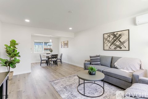 A living room with a grey couch, a coffee table, and a dining table with chairs.