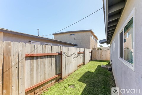 A backyard with a wooden fence and green grass.