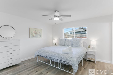 A bedroom with a bed, nightstand, and a painting on the wall.