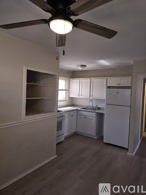 A kitchen with a ceiling fan and wooden floors.