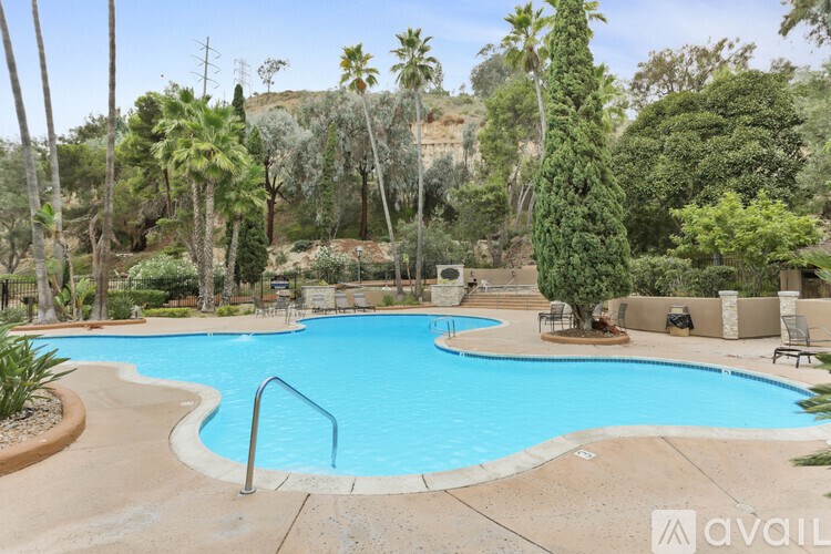 A large swimming pool surrounded by palm trees and a mountain in the background.