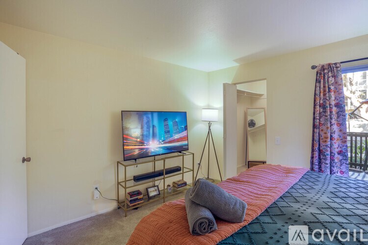 A bedroom with a bed, a television, and a window with curtains.