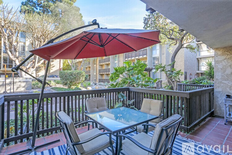A patio with a table and chairs under a red umbrella.