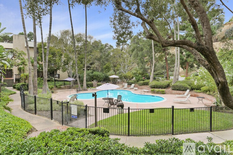 A pool surrounded by a black fence and trees.