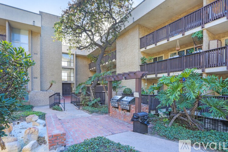 A building with a balcony and a tree in front of it.