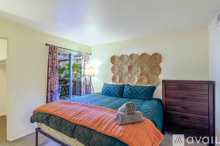 A bedroom with a bed, a dresser, and a wall decoration.