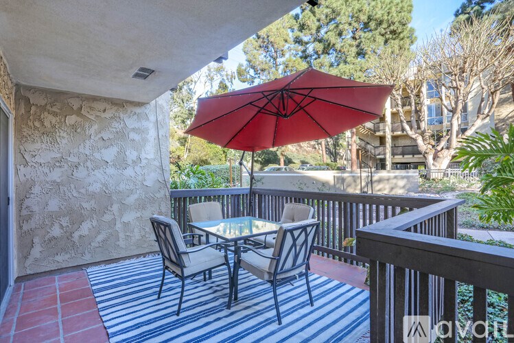 A patio with a table and chairs under a red umbrella.
