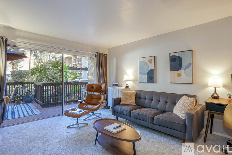 A living room with a grey couch, a brown chair, a coffee table, and a painting on the wall.