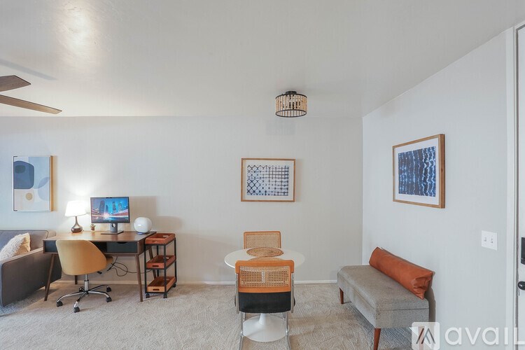 A room with a desk, chair, and two pictures on the wall.