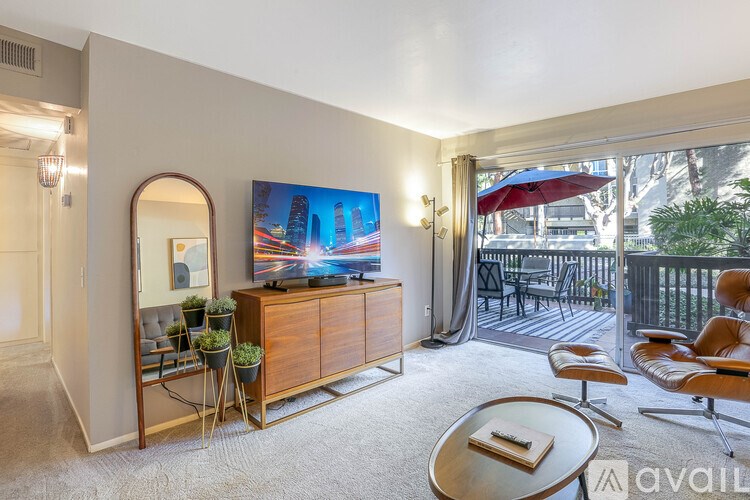 A living room with a flat screen TV and a balcony with chairs.