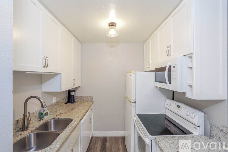 A kitchen with white cabinets and a granite countertop.