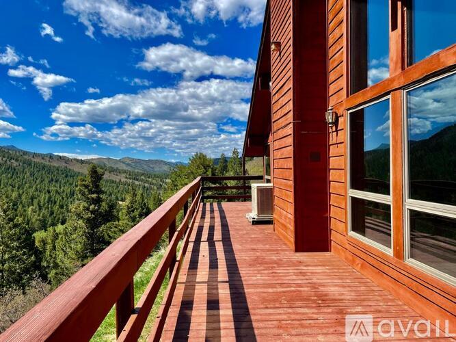 A wooden deck with a glass door leading to a balcony overlooking a mountainous landscape.