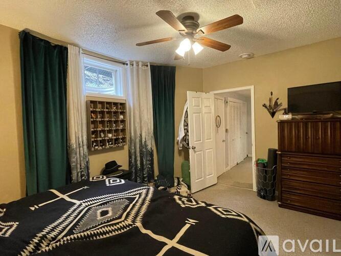 A bedroom with a bed in the center and a ceiling fan above it.