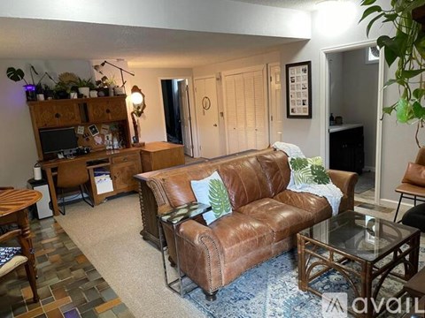 A living room with a brown leather couch and a glass coffee table.