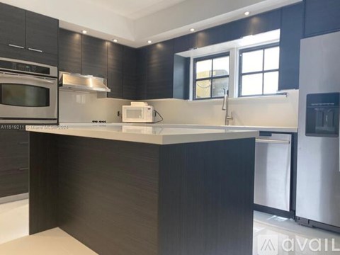 A modern kitchen with dark wood cabinets and stainless steel appliances.