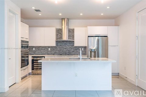 A modern kitchen with white cabinets and a central island.