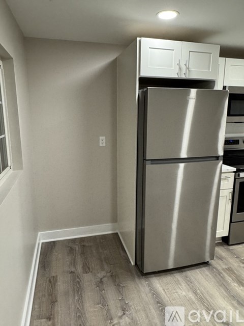 A stainless steel refrigerator in a kitchen with wooden flooring.