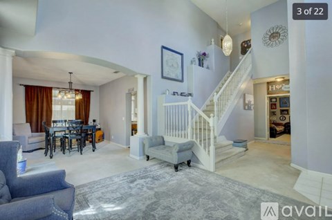 A living room with a grey sofa and a dining table with chairs.