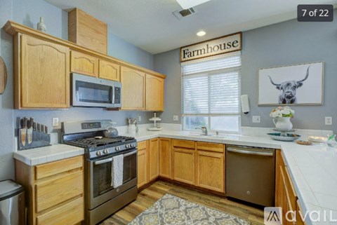 A kitchen with wooden cabinets and a Farmhouse sign.