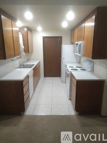 A kitchen with brown cabinets and white appliances.