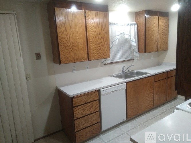 A kitchen with wooden cabinets and a white dishwasher.