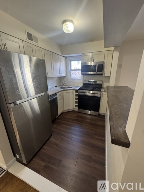 A kitchen with a stainless steel refrigerator and wooden floors.