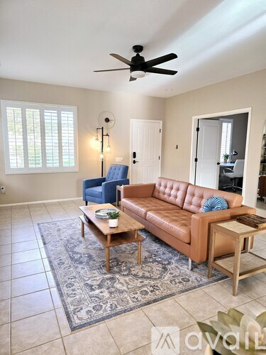 A living room with a brown leather couch, a blue chair, and a wooden coffee table.