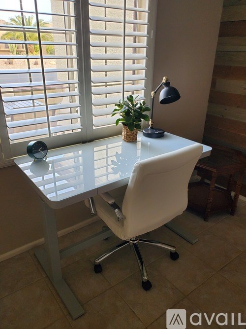 A white desk with a plant and a lamp on it.