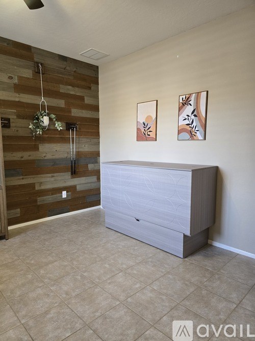 A room with a wooden wall and a grey dresser.
