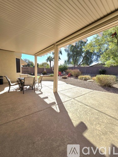 A patio with chairs and a table is covered by a roof.