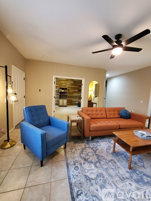 A living room with a blue chair and an orange couch.