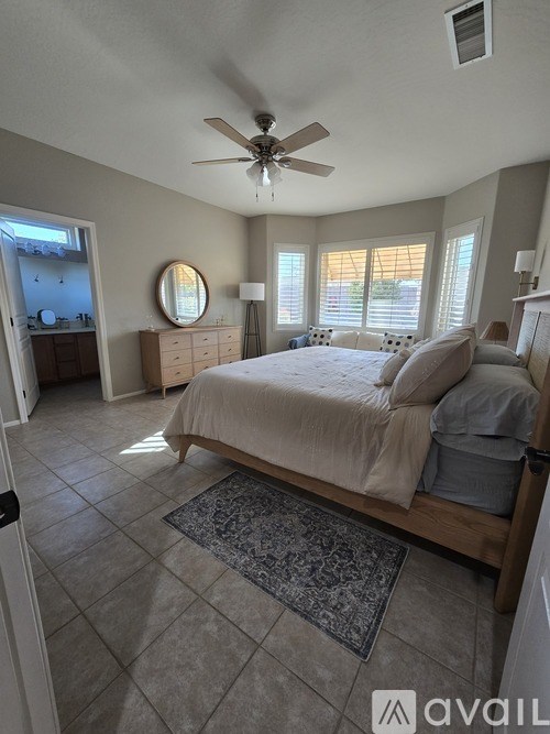 A bedroom with a large bed and a ceiling fan.
