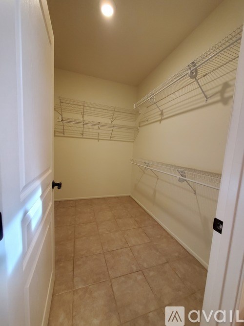 A white closet with a white door and a white shelf.