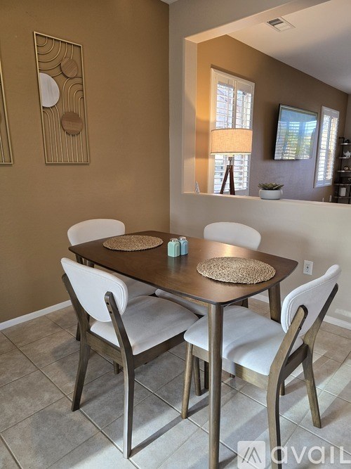 A dining table with four chairs and a decorative wall hanging.