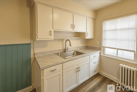 A kitchen with white cabinets and a green wall.
