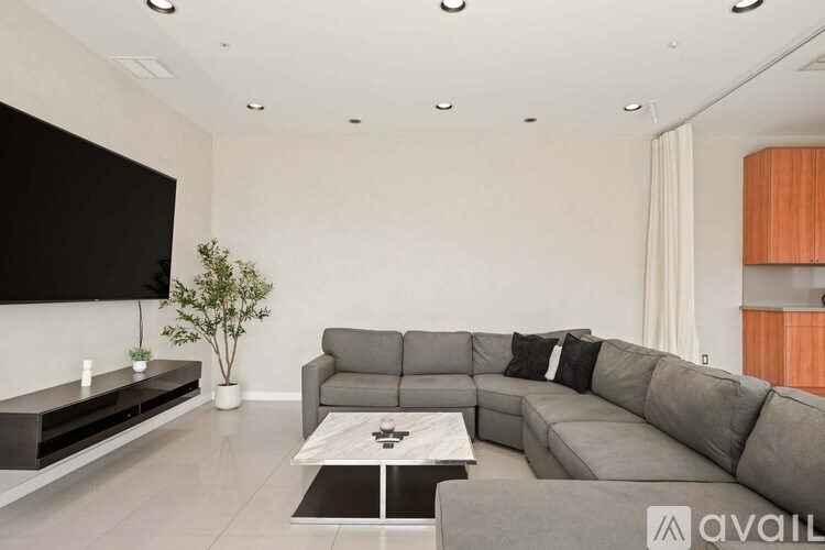 A modern living room with a grey sofa and a large window overlooking the city.