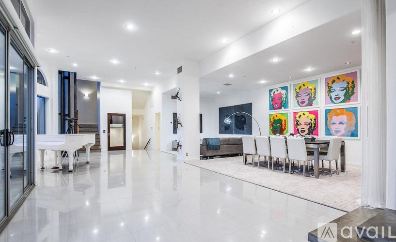 A spacious, modern living room with a dining area and a kitchen in the background.