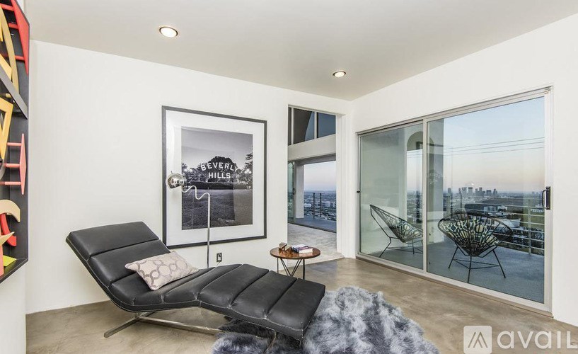 A living room with a black leather chair and a framed picture of Evergreen Hills.