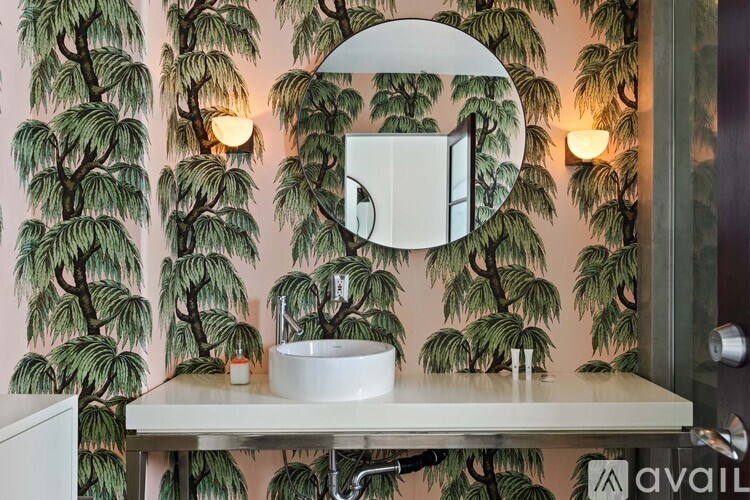 A living room with a black couch and a large painting on the wall.