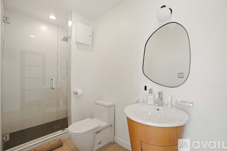 A bathroom with a toilet, sink, mirror, and a window.