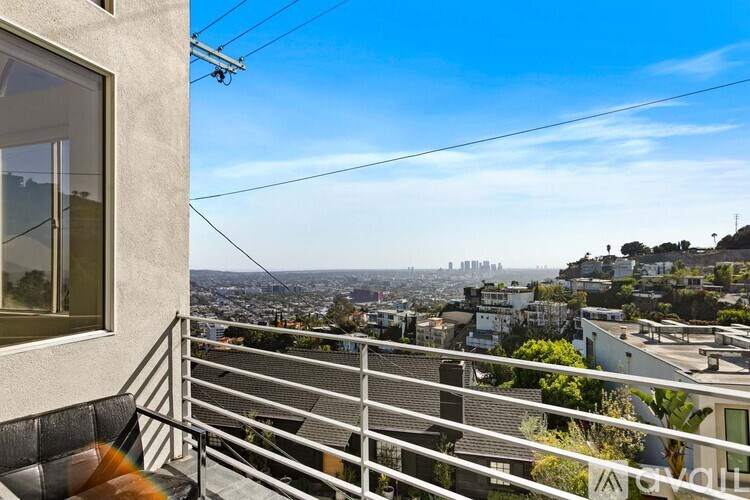 A dog is sitting on a balcony looking out at a cityscape.