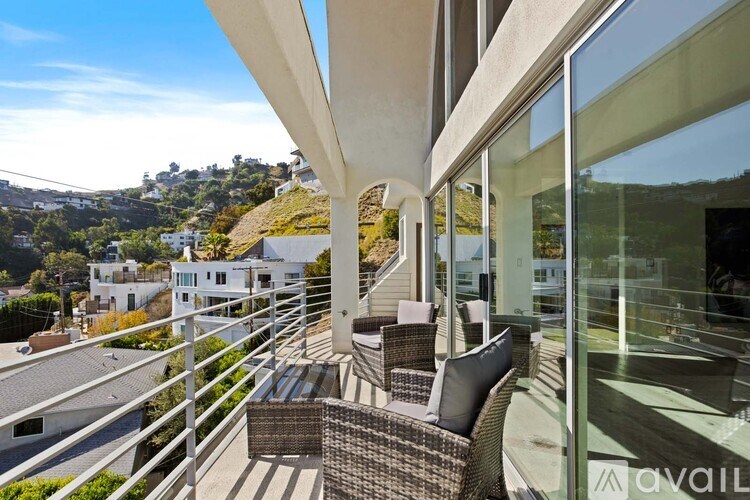 A balcony with a wicker chair and a table with a glass top.