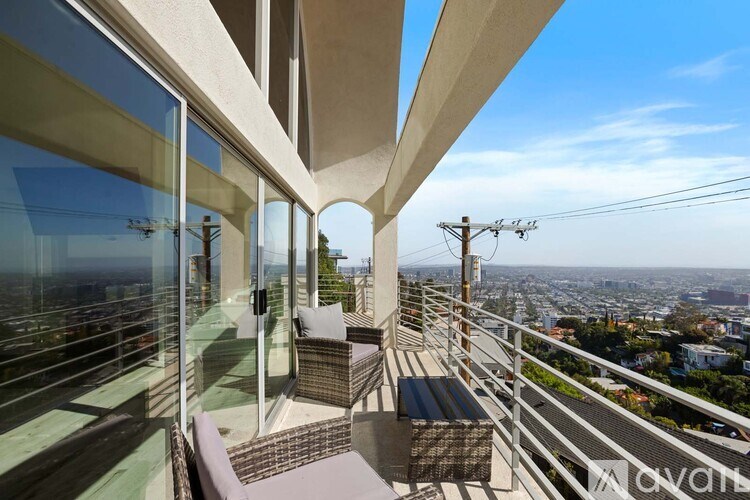 A balcony with a table and chairs overlooking a cityscape.
