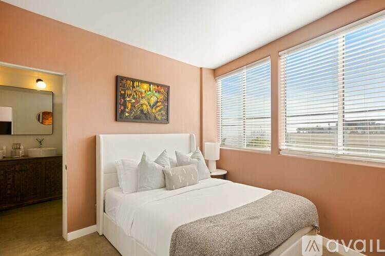 A bedroom with a large bed and a painting on the wall.